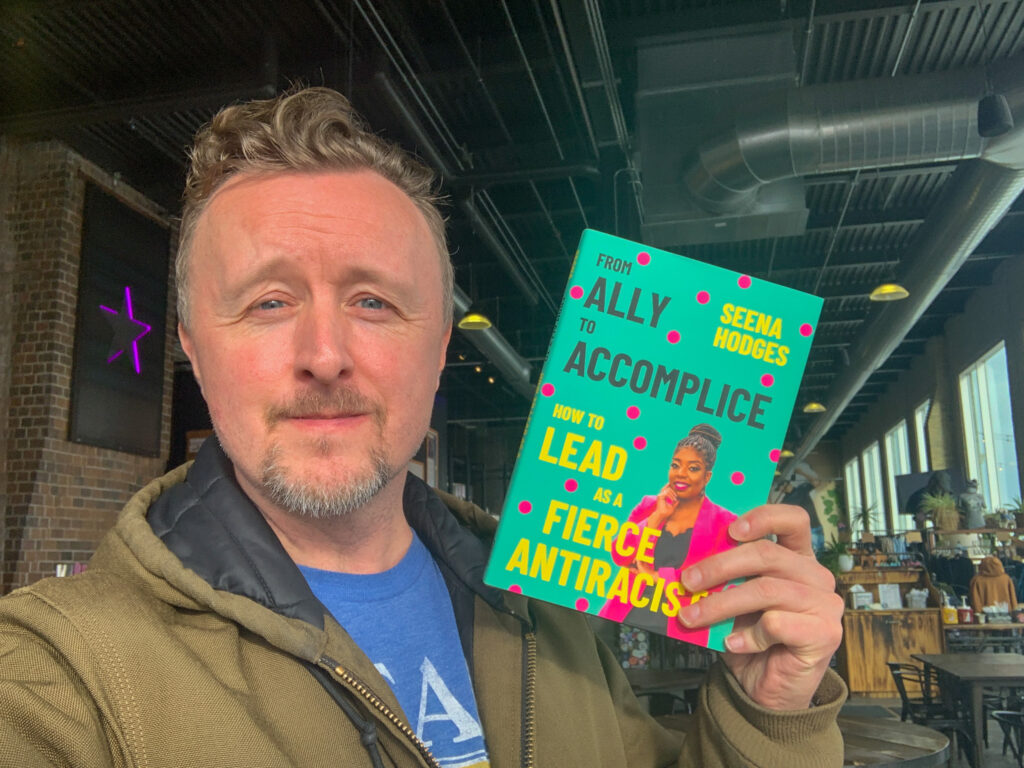 Paul Cram holding up Seena Hodges book "From Ally to Accomplice" at Forgotten Star Brewing in Minnesota